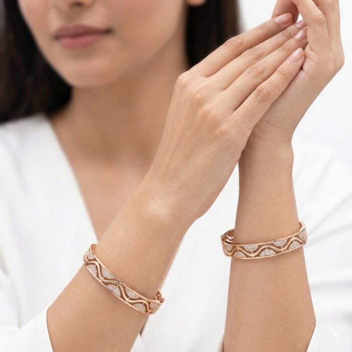123-(3) "Pair of 18k gold minimalist bangles featuring a wave cut-out design with small stones, size 2.5, by OVJ Jewels."