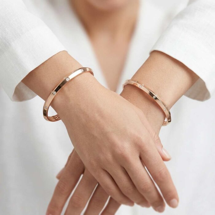 123-(6) Two 18k rose gold minimalist bangles with flush-set stones and geometric inner detailing, size 2.6, by OVJ Jewels.